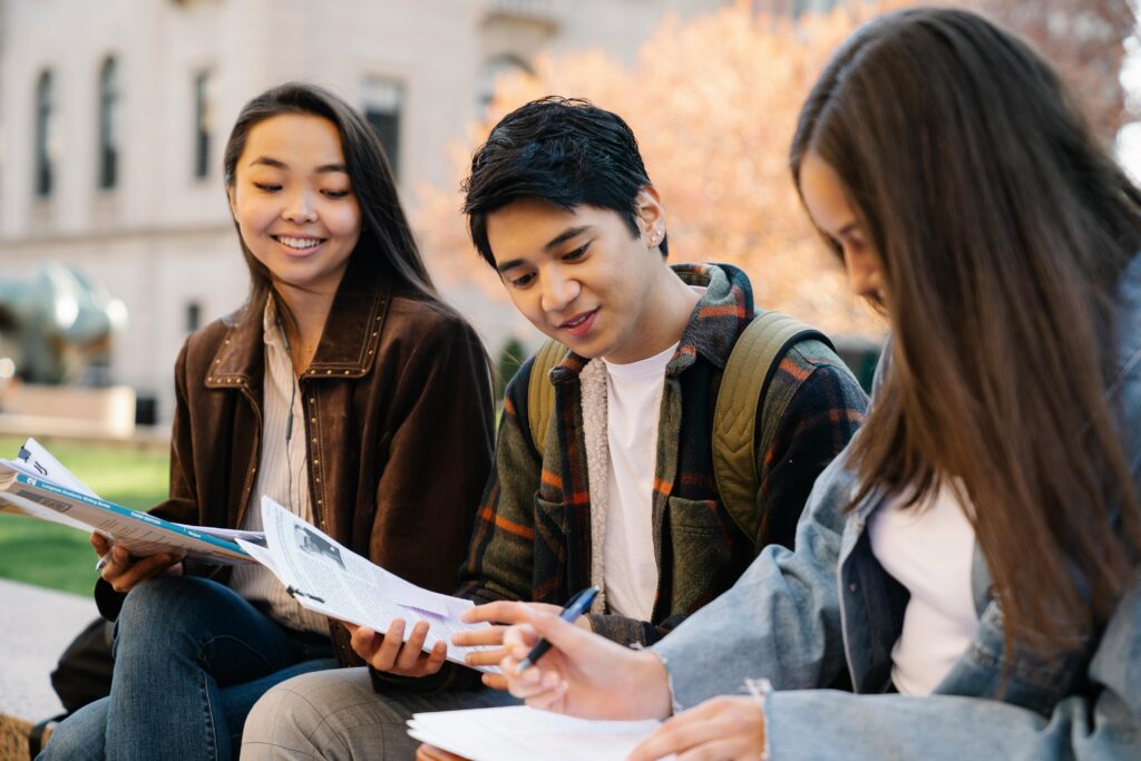 Group of college students studying together on campus in autumn.